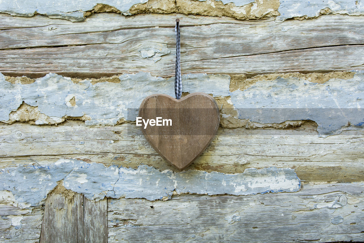 Close-up of wooden heart shape hanging against wall