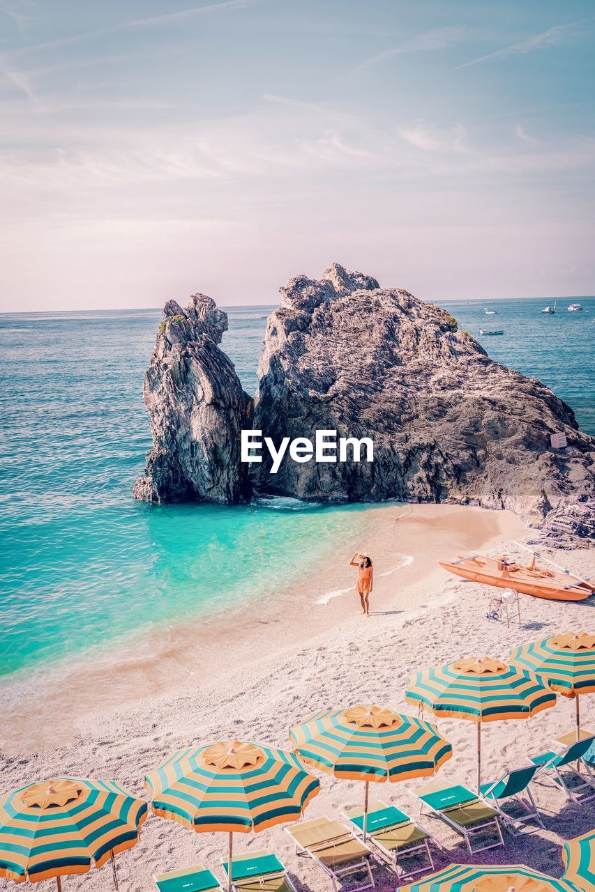 Woman standing by umbrellas on shore at beach