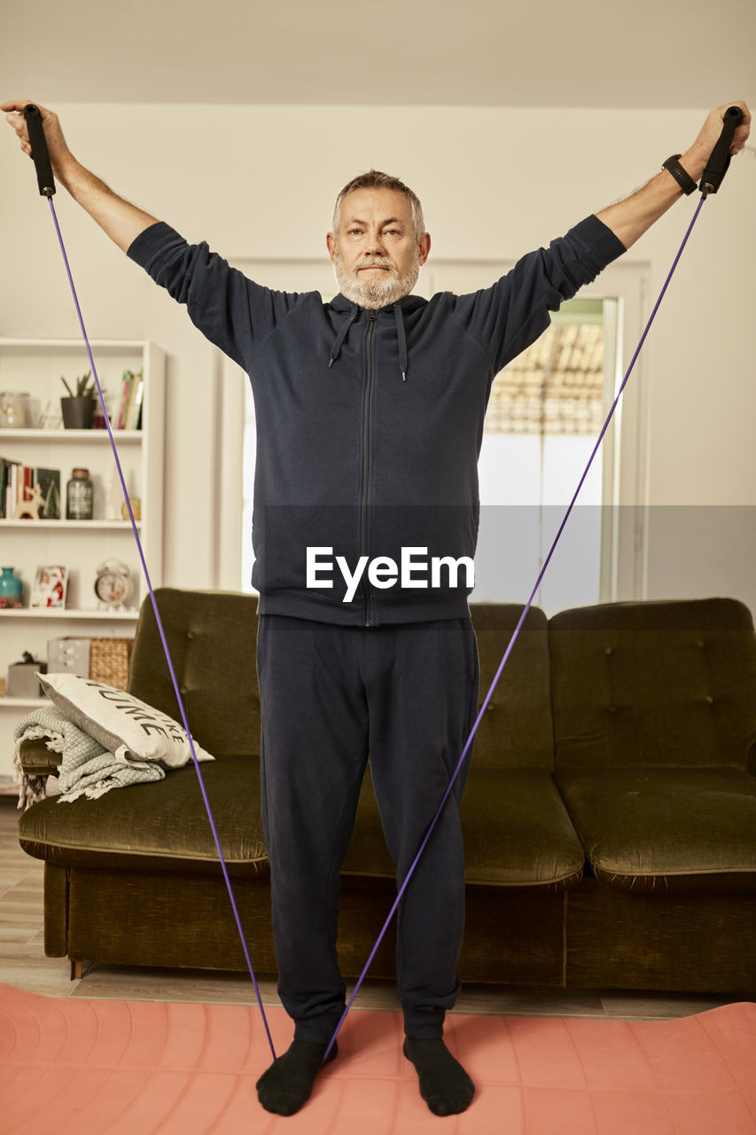 Senior man exercising with resistance band at home