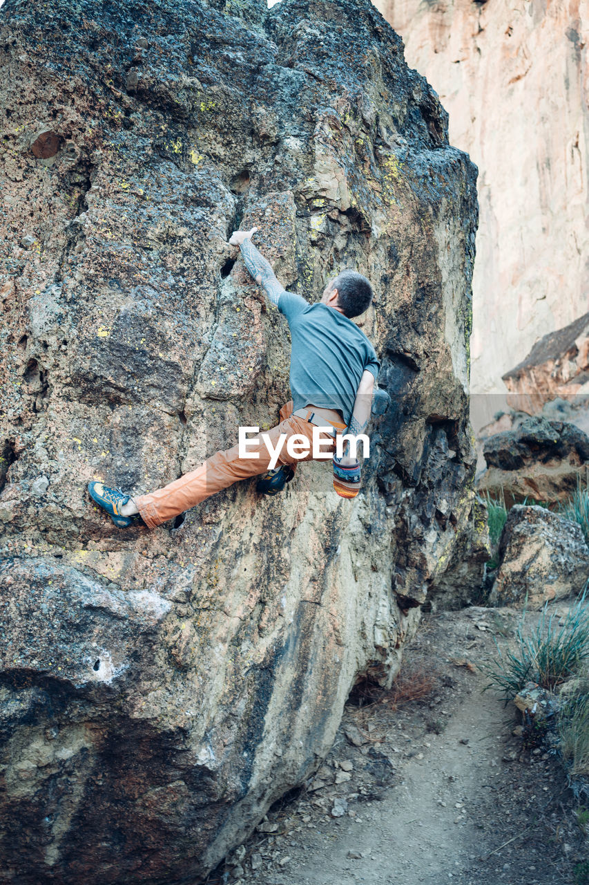 Male climber getting to the top of the boulder in smith rock park