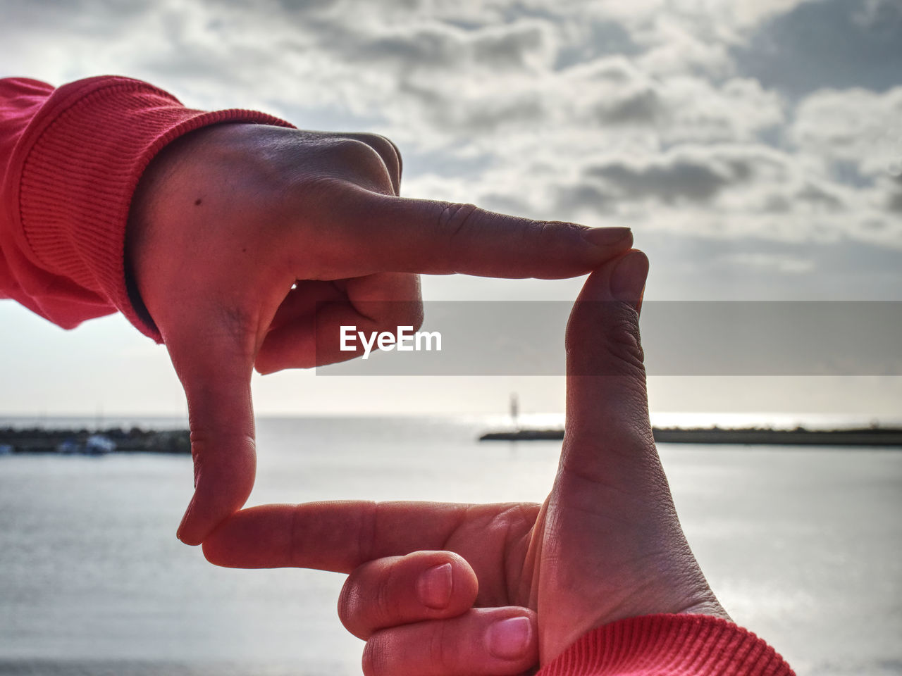 Fingers picture frame on sunrise seaside. sunlight on beach. female hand gesture in love concept