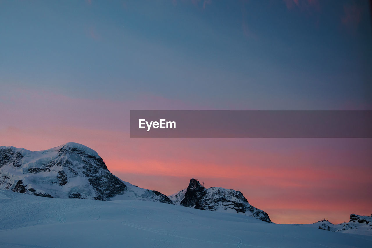 Scenic view of snow covered mountains against sky during sunset