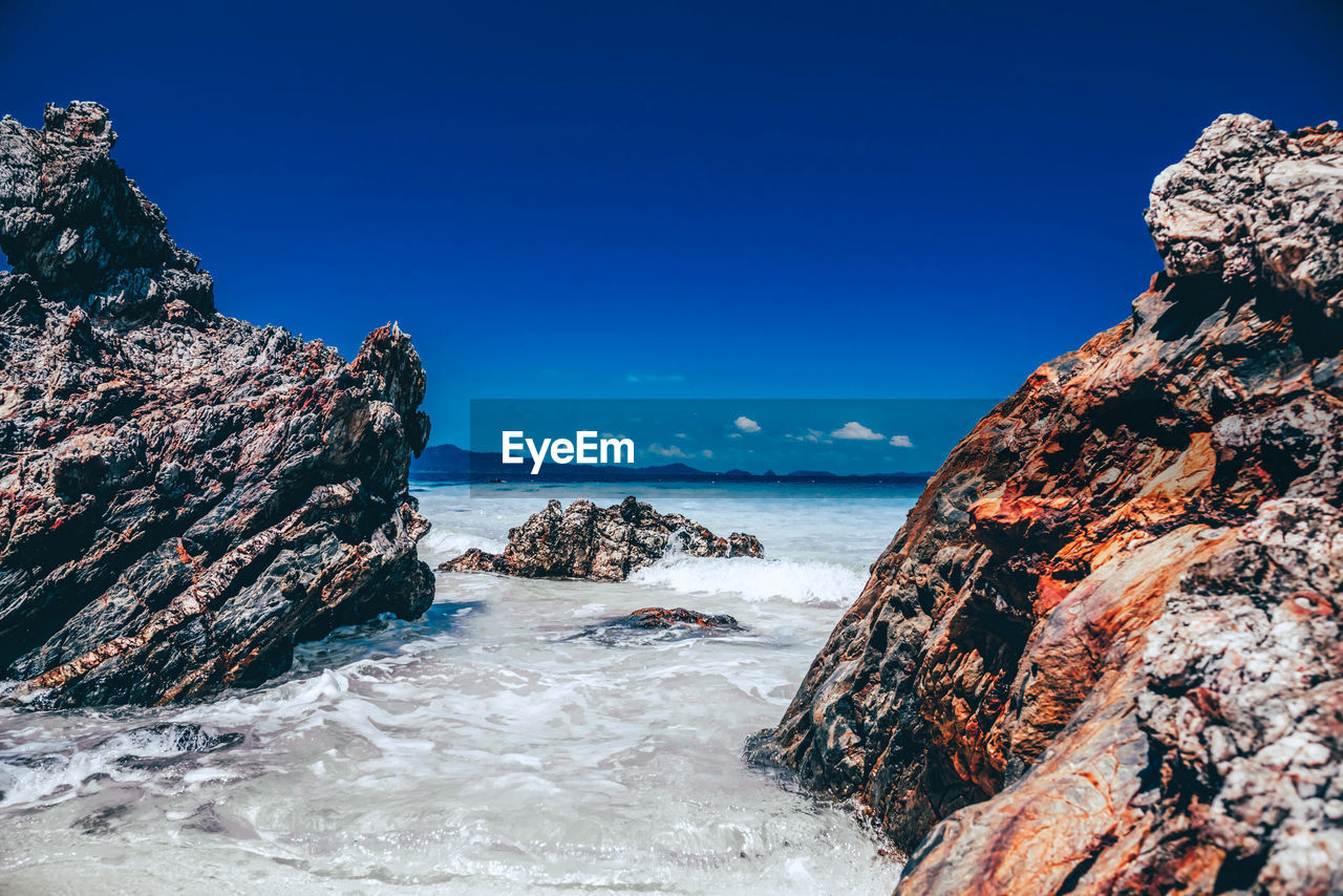 Rock formations in sea against blue sky