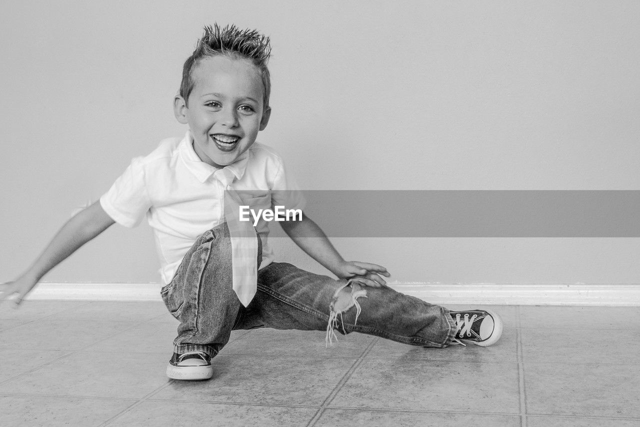 Cheerful young boy in a breakdance posture on the floor