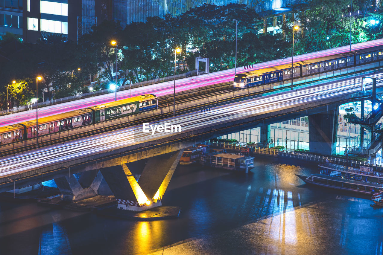 Railway bridge over river in city at night