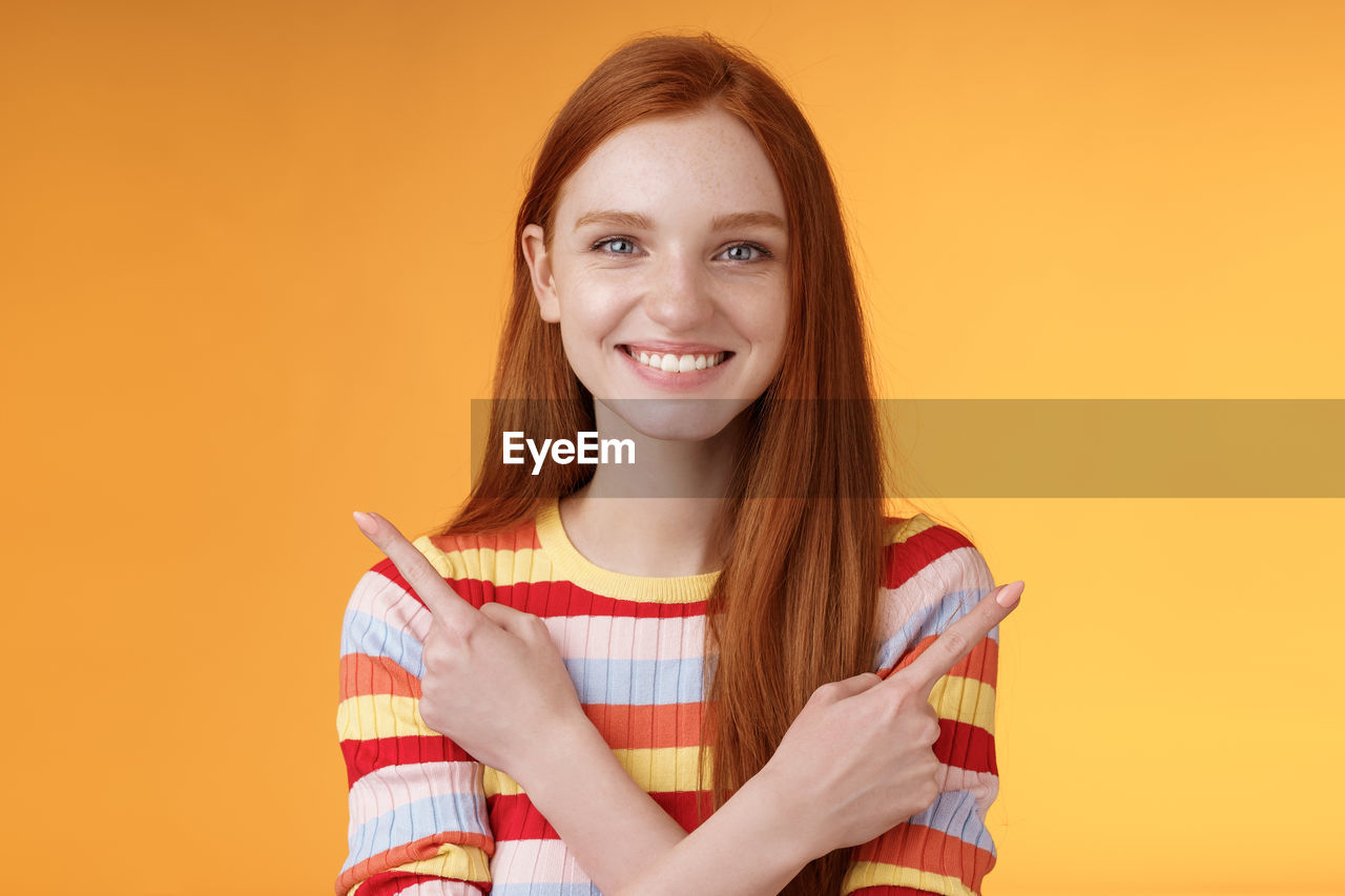 PORTRAIT OF A SMILING YOUNG WOMAN OVER YELLOW BACKGROUND