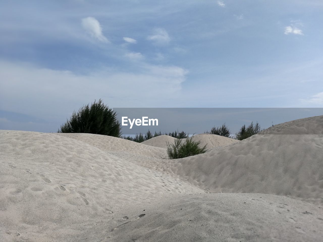 Scenic view of sand dunes against sky