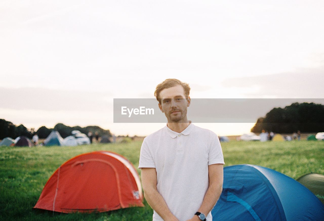 Portrait of man standing on camping field against sky