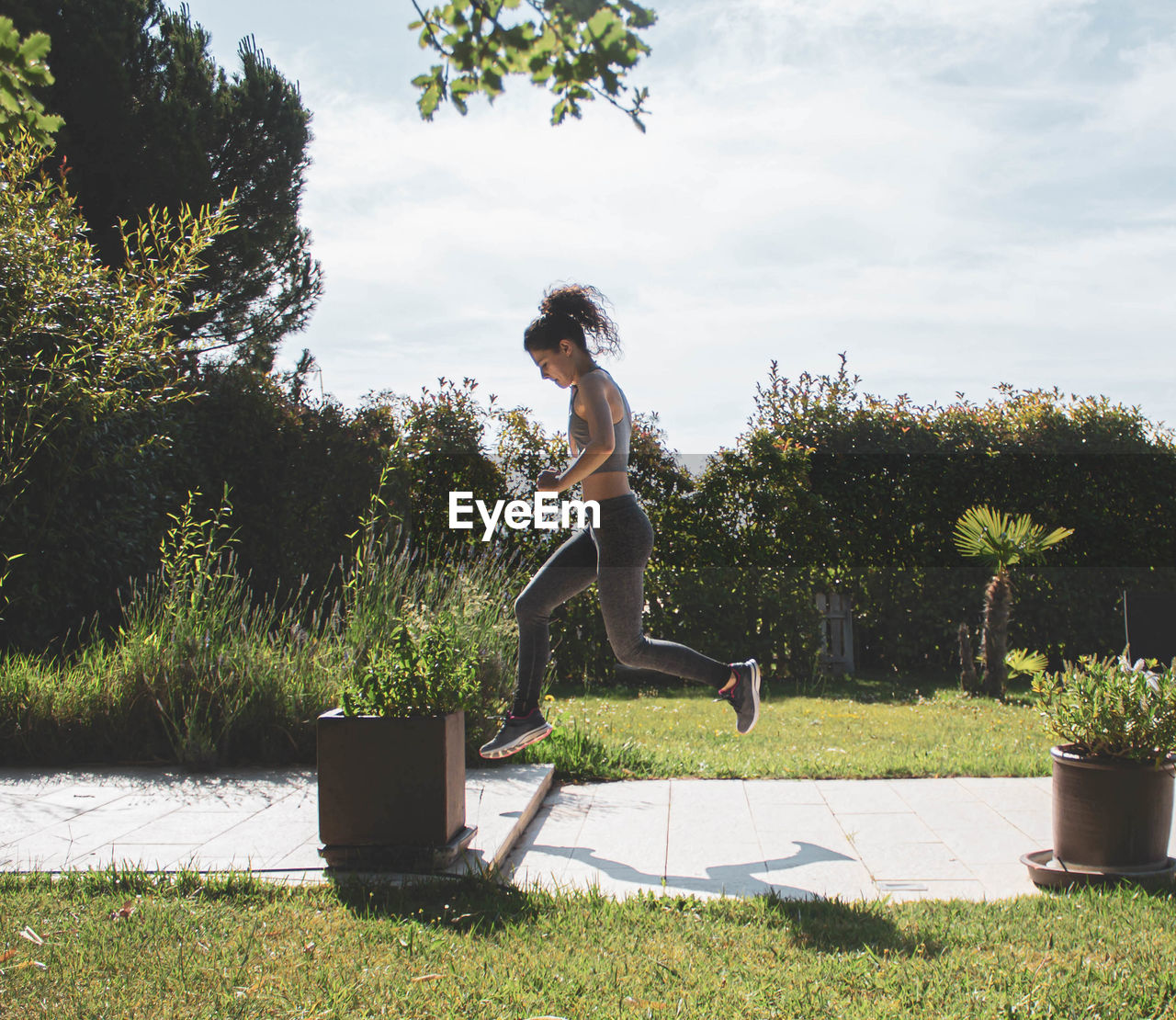 Young woman exercising in her home garden