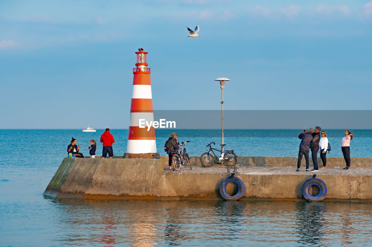 PEOPLE ON LIGHTHOUSE AGAINST SEA