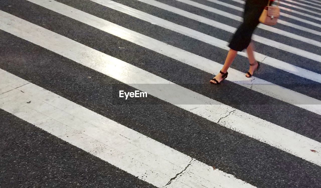 Low section of woman walking on zebra crossing