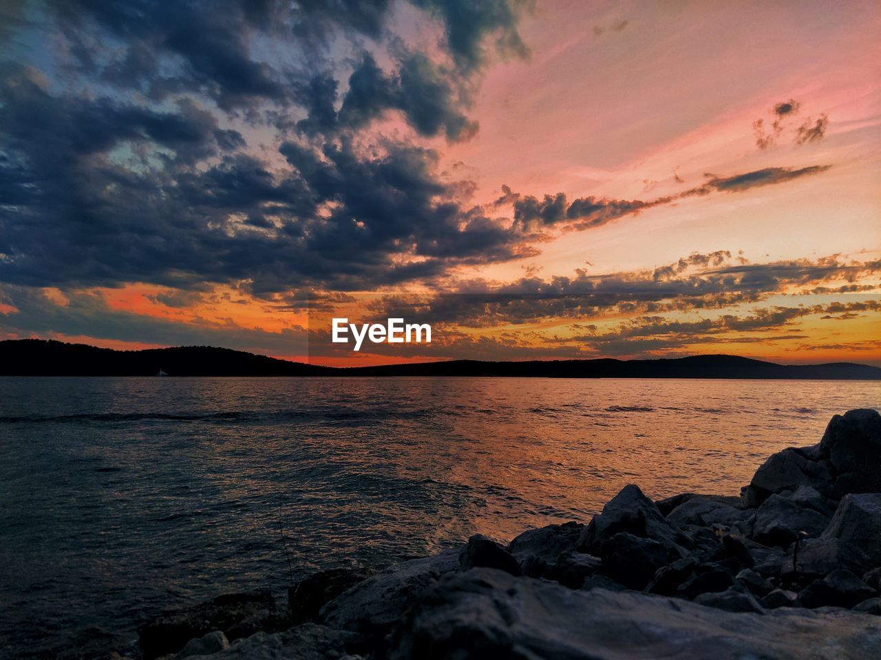 scenic view of sea against cloudy sky during sunset