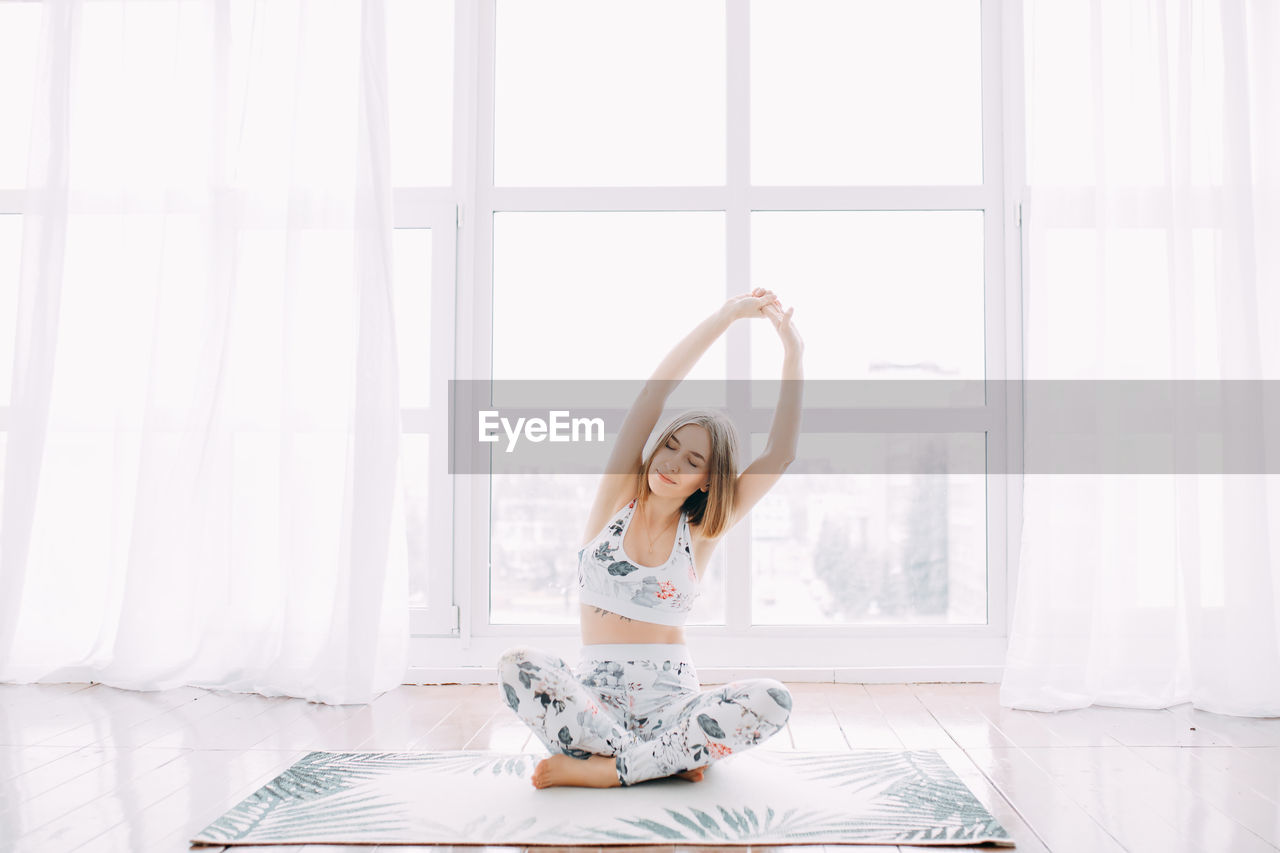 Girl in a sports uniform does exercises, physical exercises, yoga and stretches at home