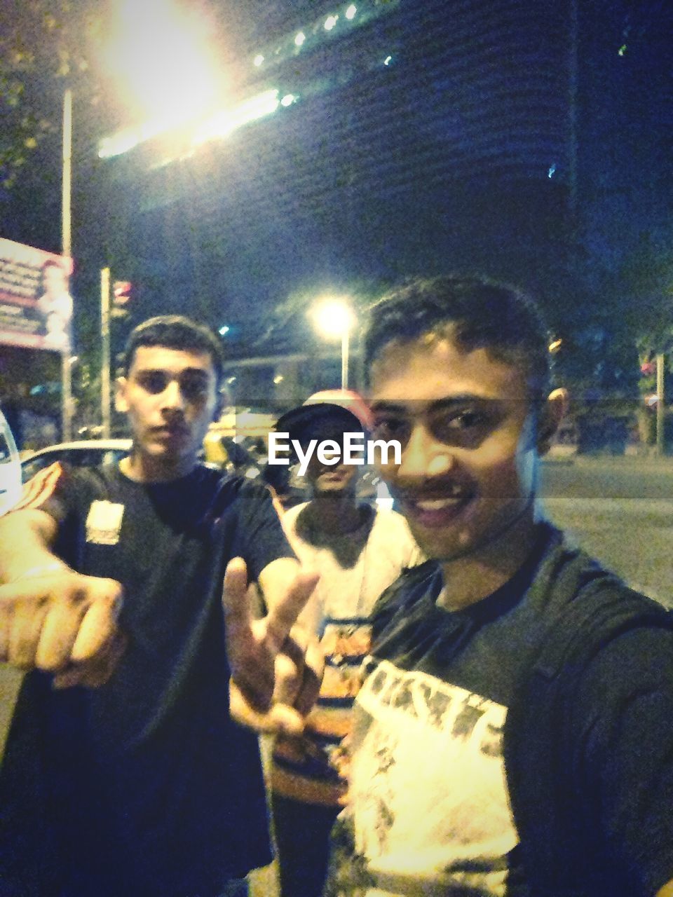 PORTRAIT OF MAN HOLDING SUNGLASSES IN CITY AT NIGHT