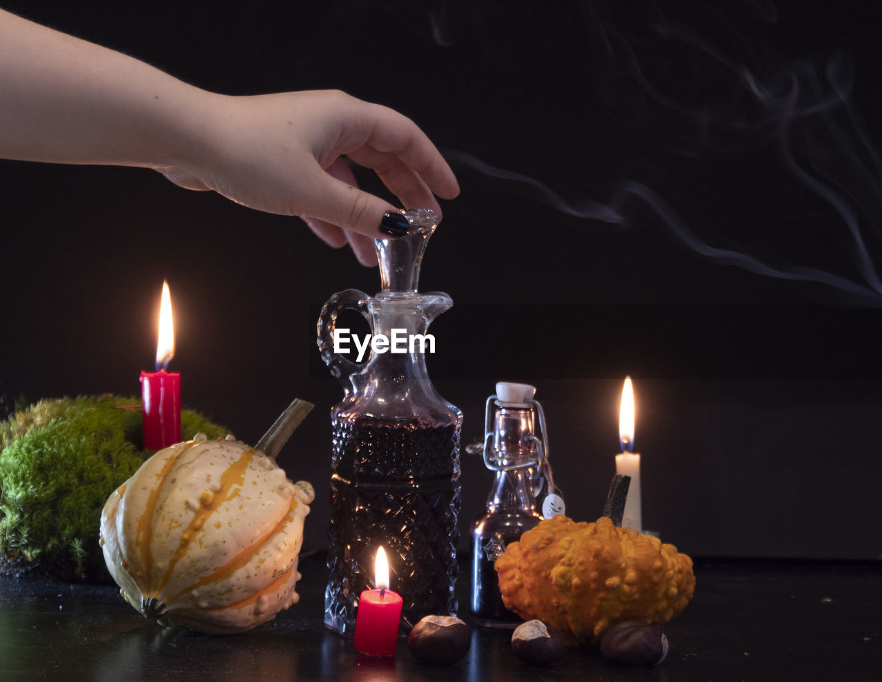 CLOSE-UP OF HAND WITH CANDLES AGAINST BURNING CANDLE