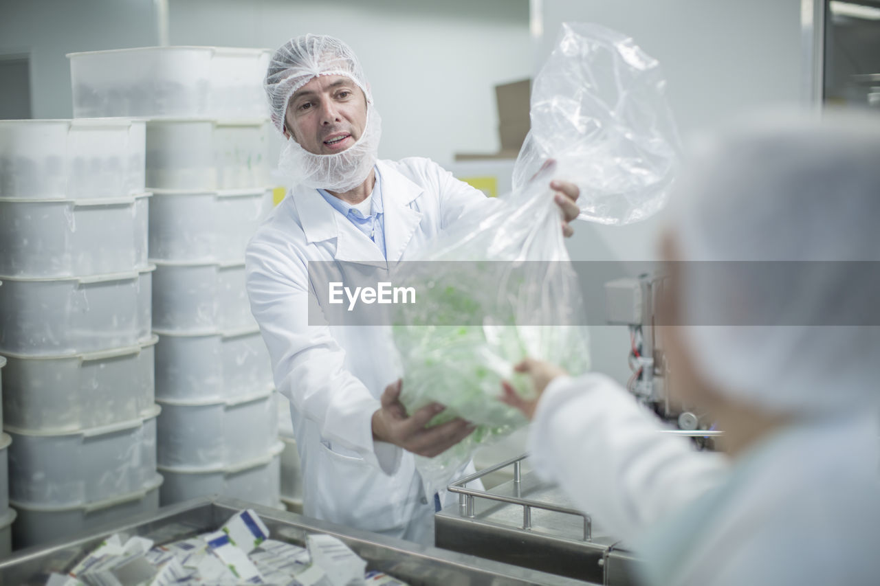 Lab worker in pharmaceutical plant handing over plastic bag