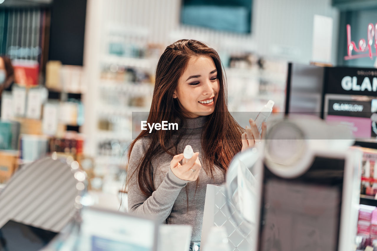 Smiling young woman shopping at cosmetic store