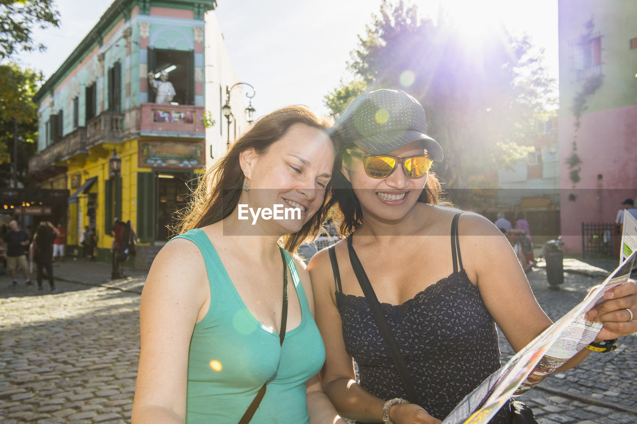 Two female friends looking at city map in la boca / buenos aires