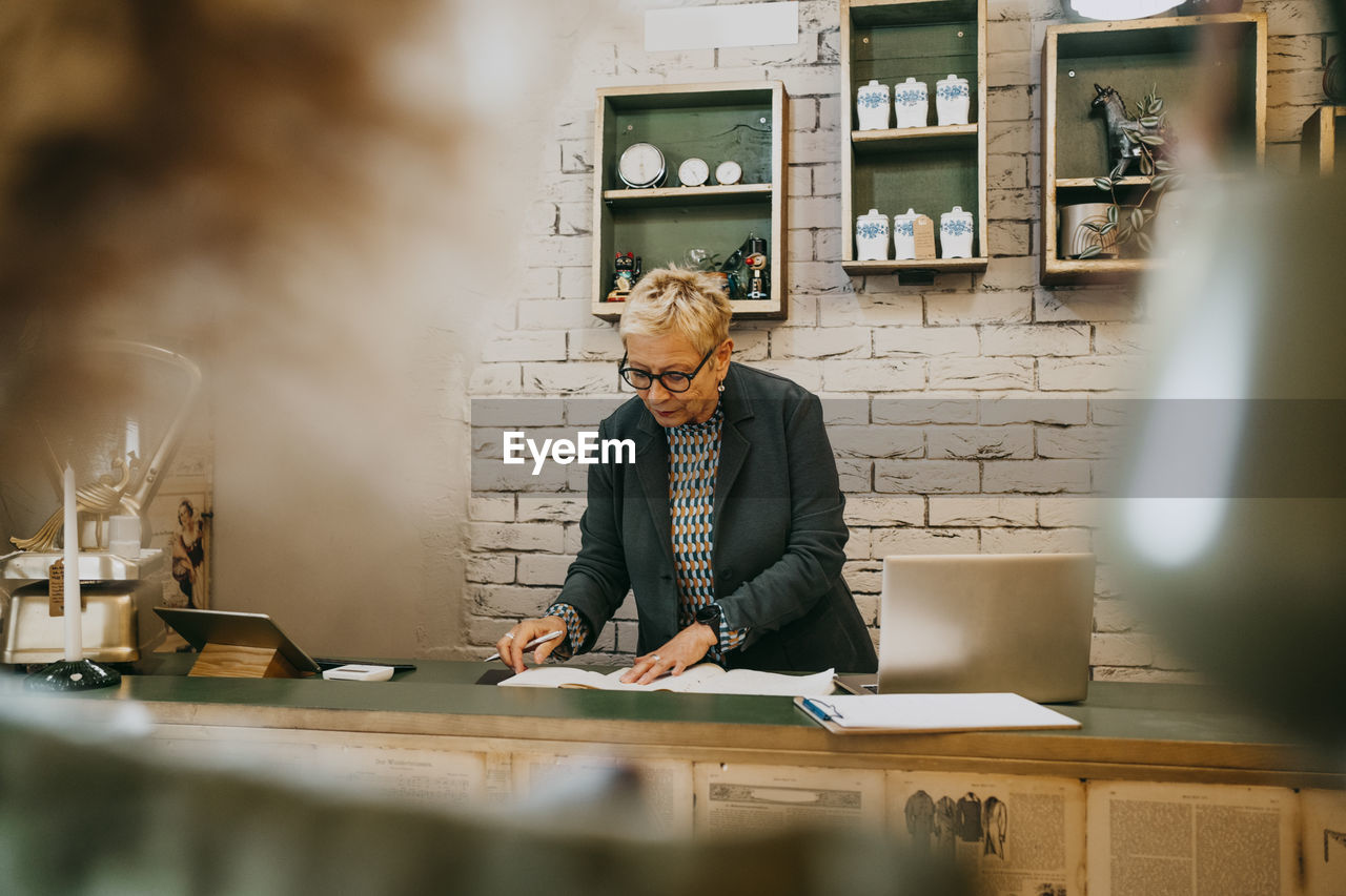 Senior female entrepreneur examining documents at decor shop