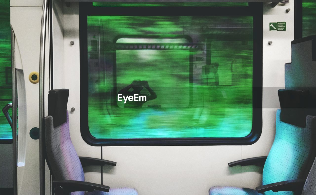 Reflection of man photographing on train window