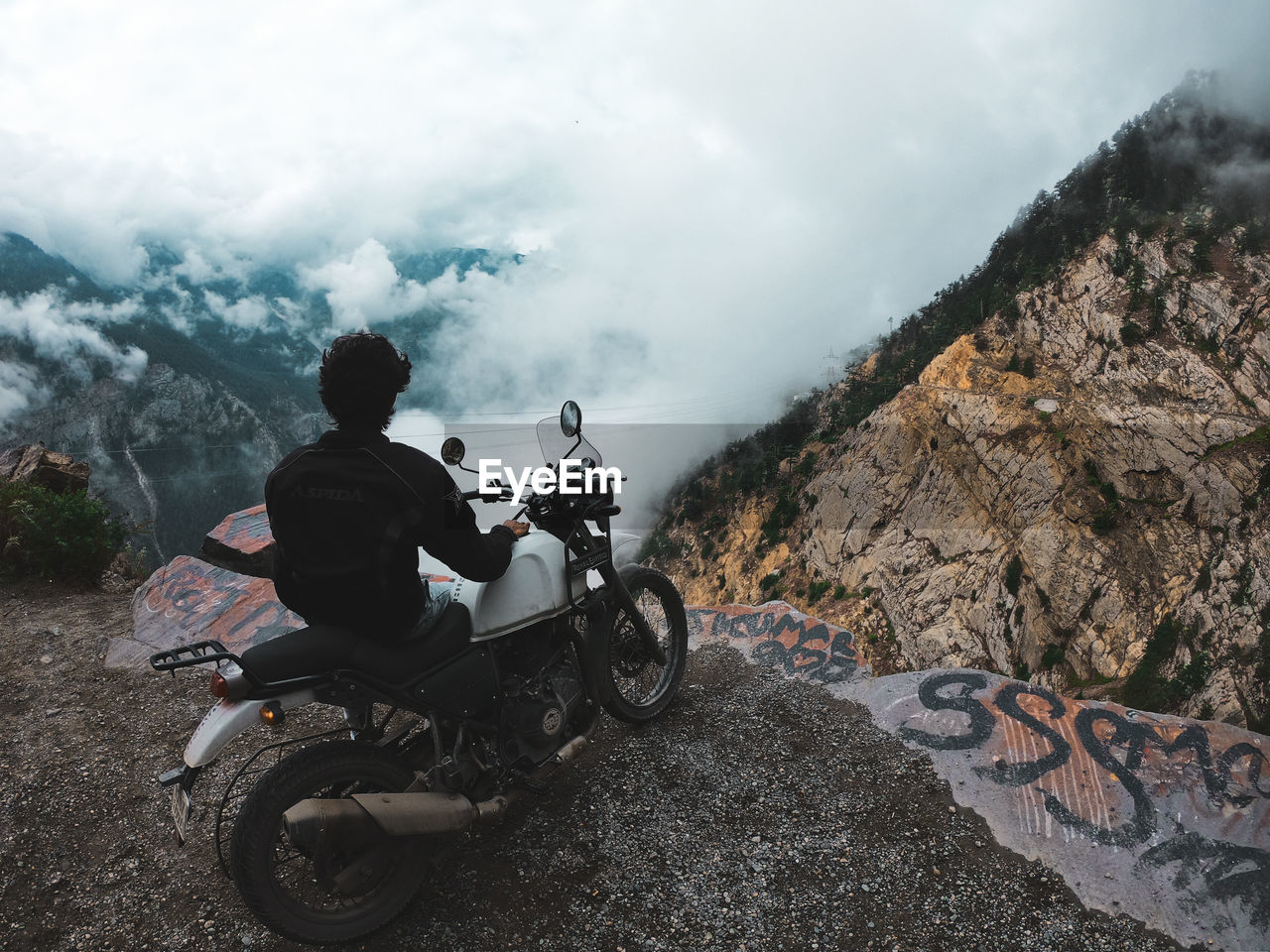 REAR VIEW OF MAN RIDING MOTORCYCLE AGAINST SKY