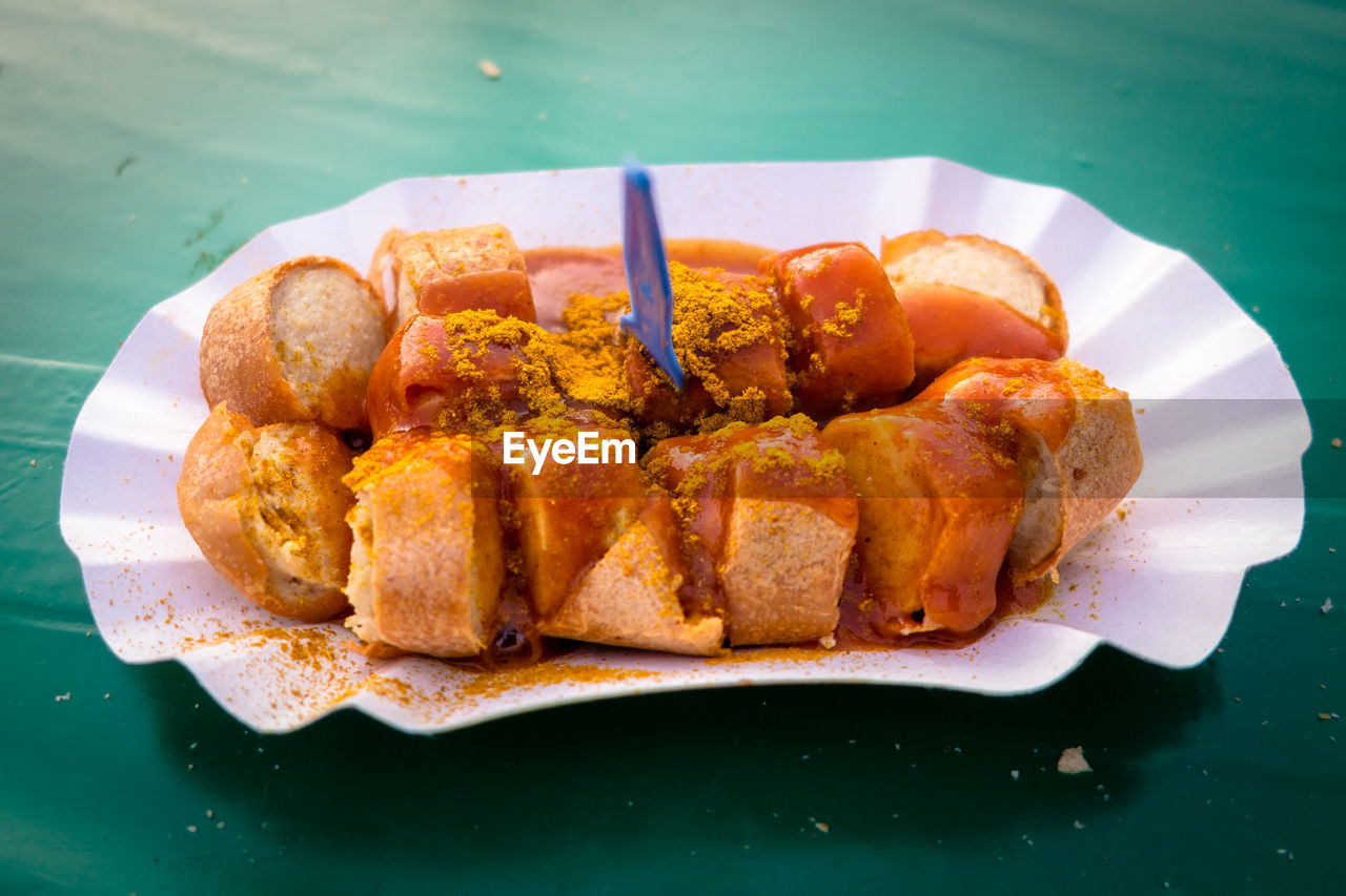 Close-up of currywurst served in paper plate on table