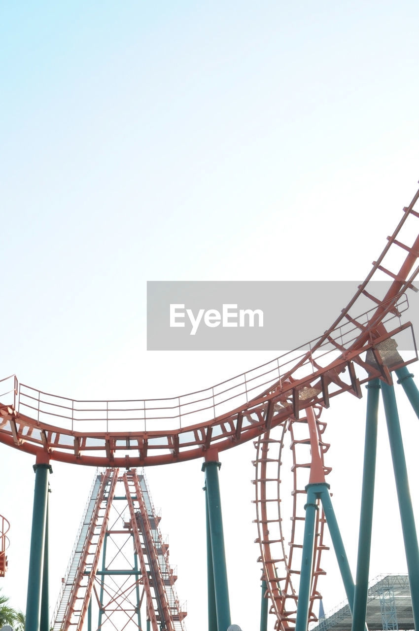Low angle view of roller coaster ride in amusement park against clear sky