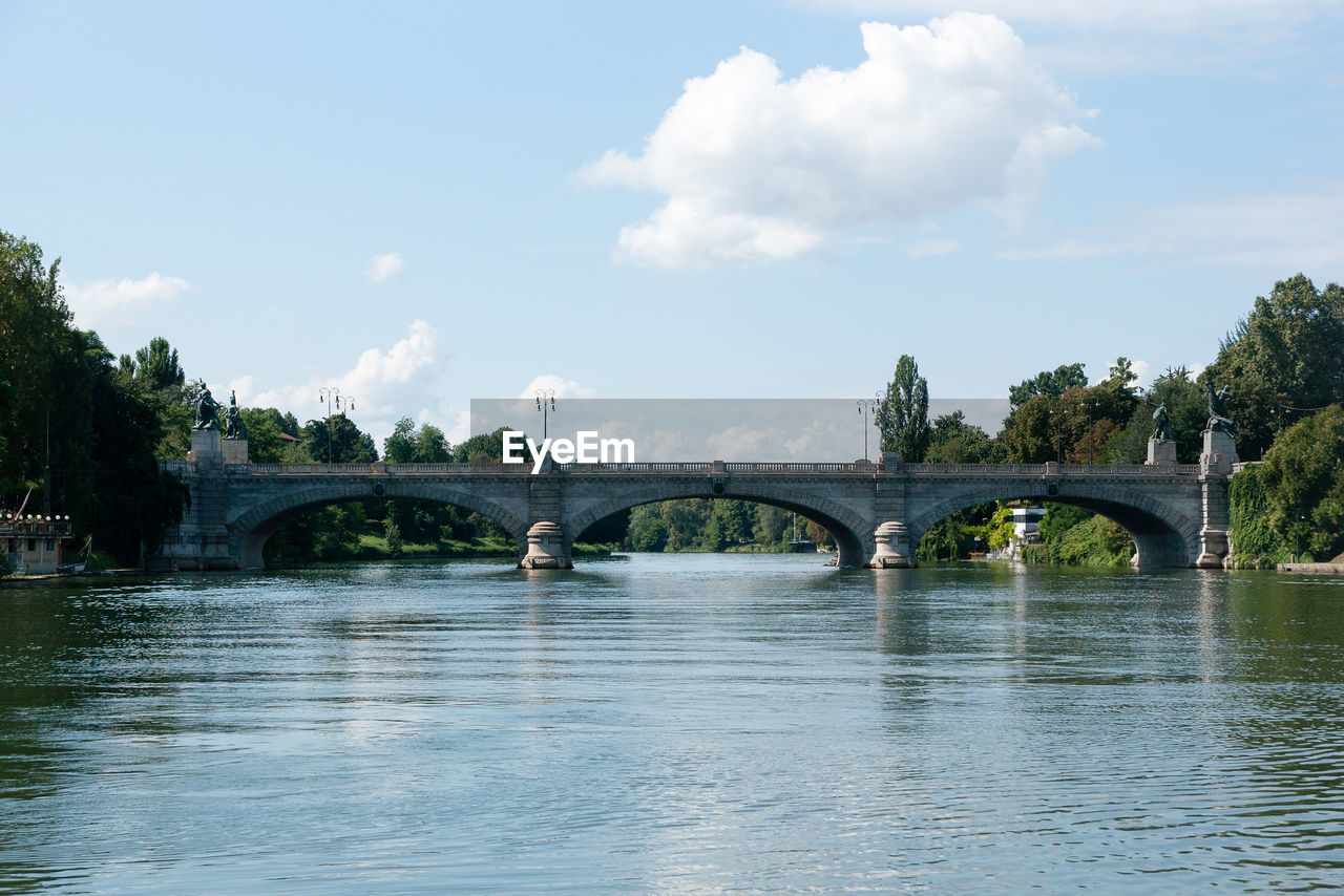 Arch bridge over river against sky