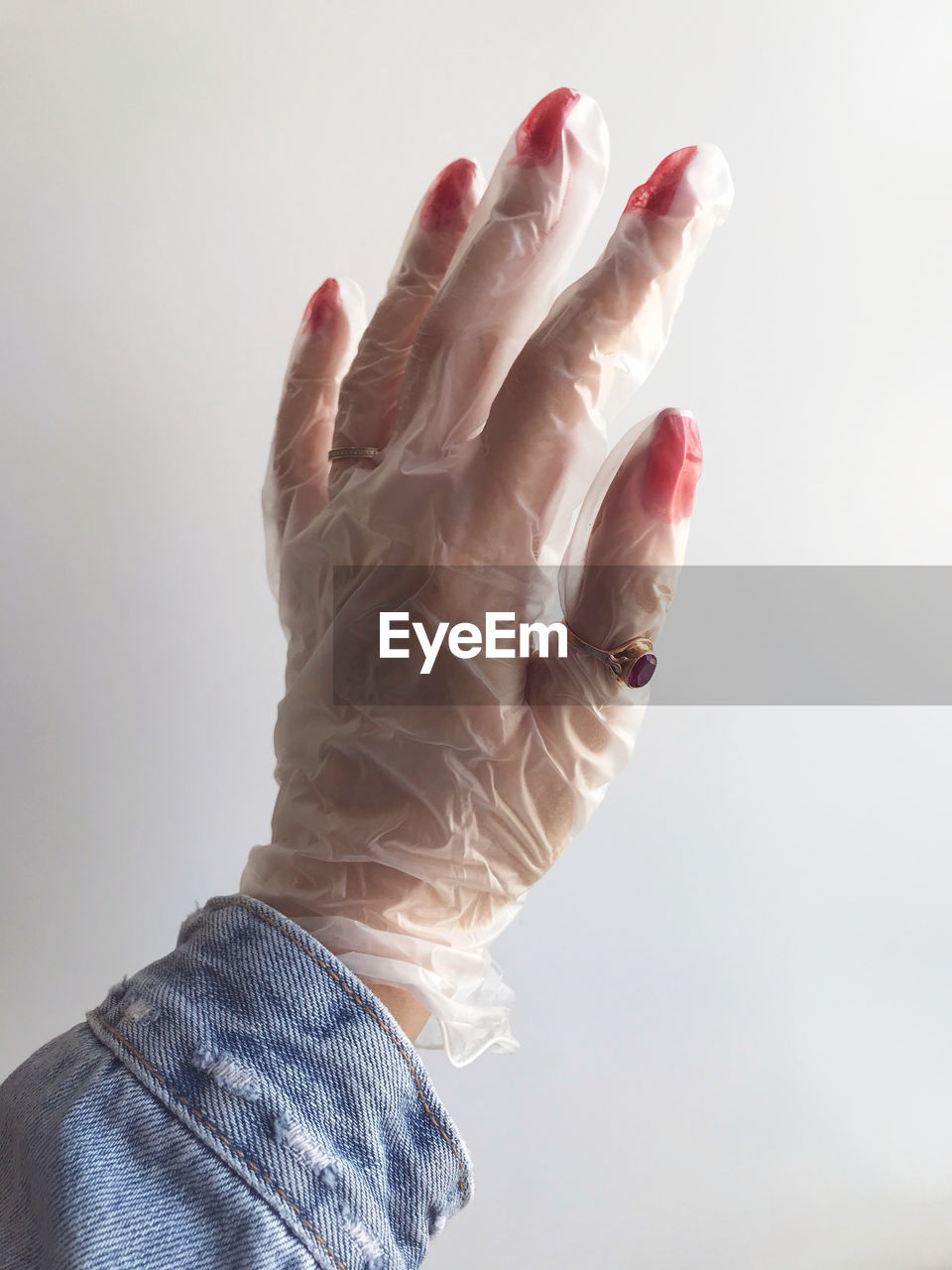 Cropped hand of woman wearing protective glove against white background