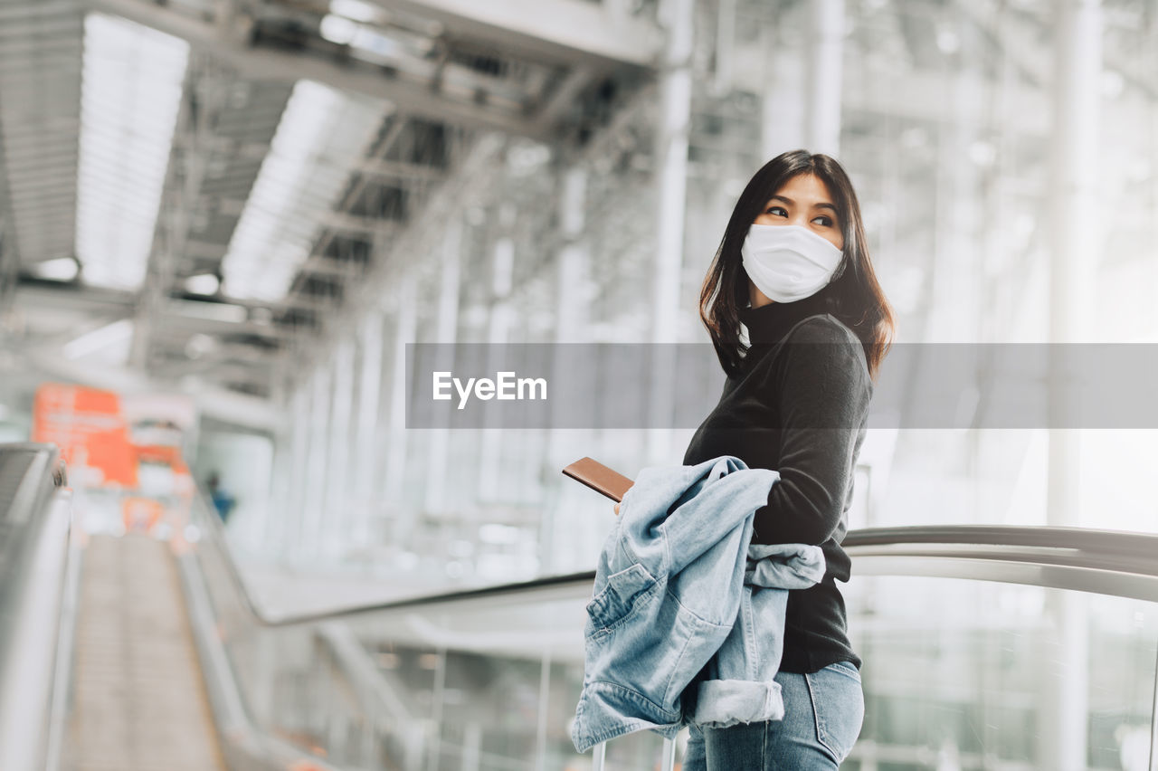 Woman looking away while standing at railroad station