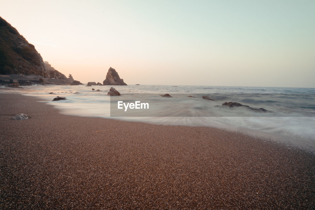 SCENIC VIEW OF BEACH AGAINST SKY DURING SUNSET