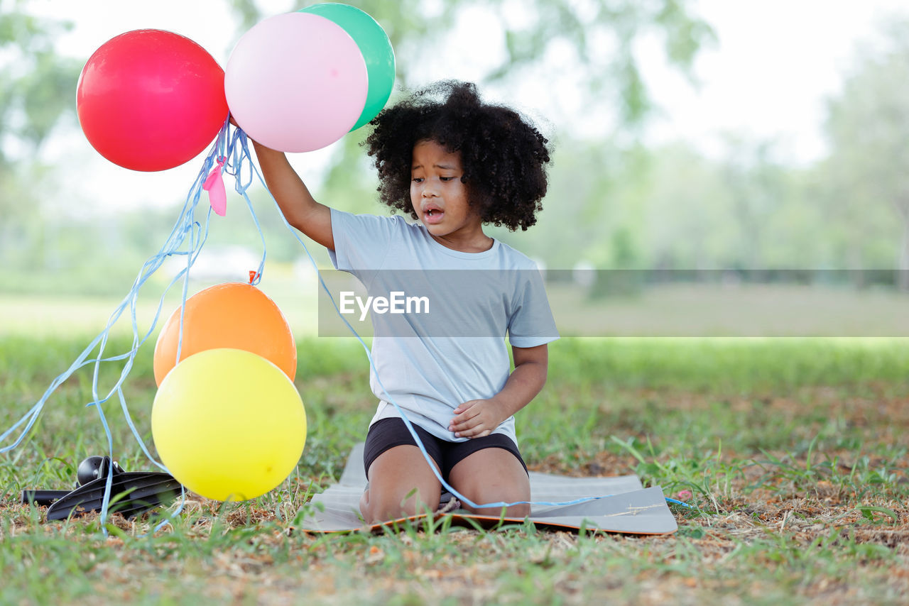 Girl holding balloons in field