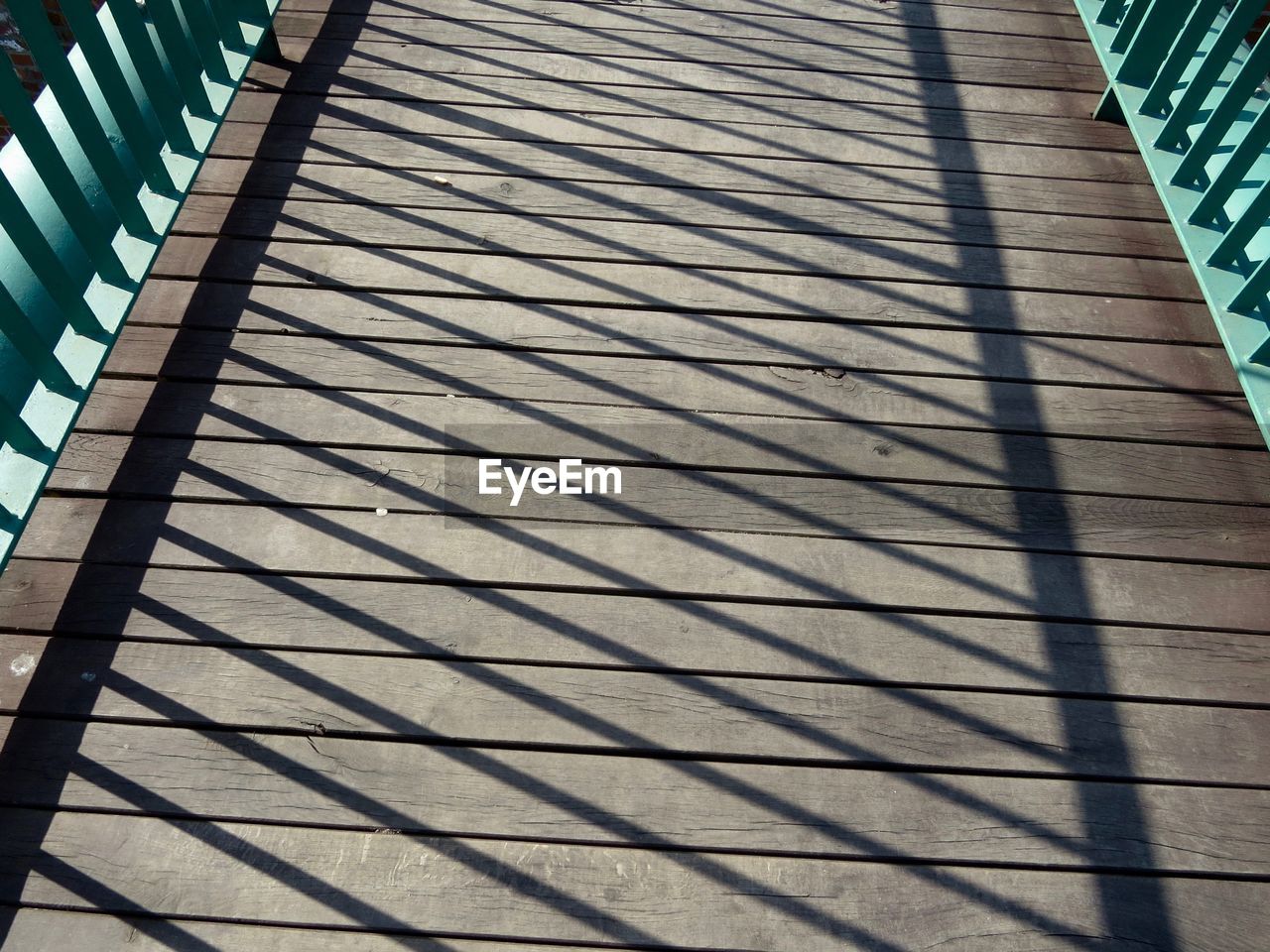 Shadow of railing on wooden bridge