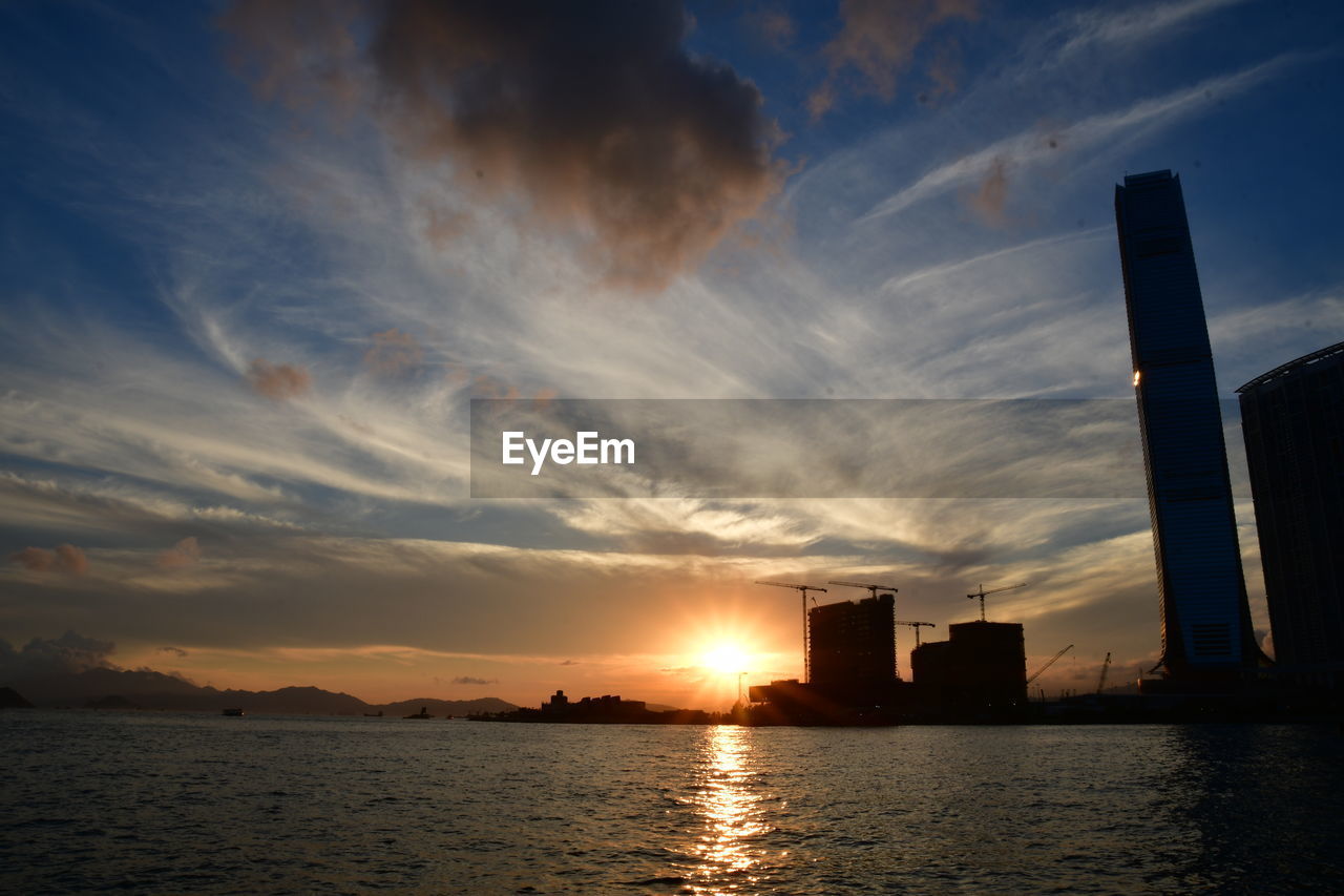 Scenic view of sea by buildings against sky during sunset