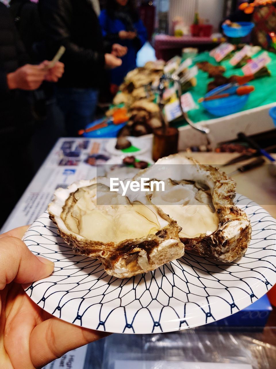 Cropped image of hand holding seashells in plate at market stall