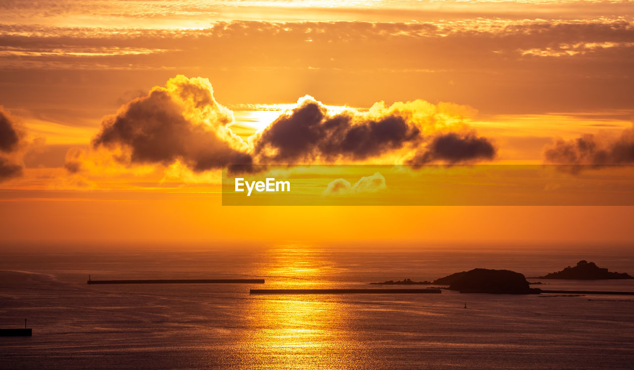 Scenic view of sea against dramatic sky during sunset