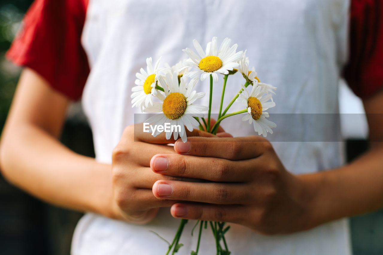 Holding a bouquet of daisies