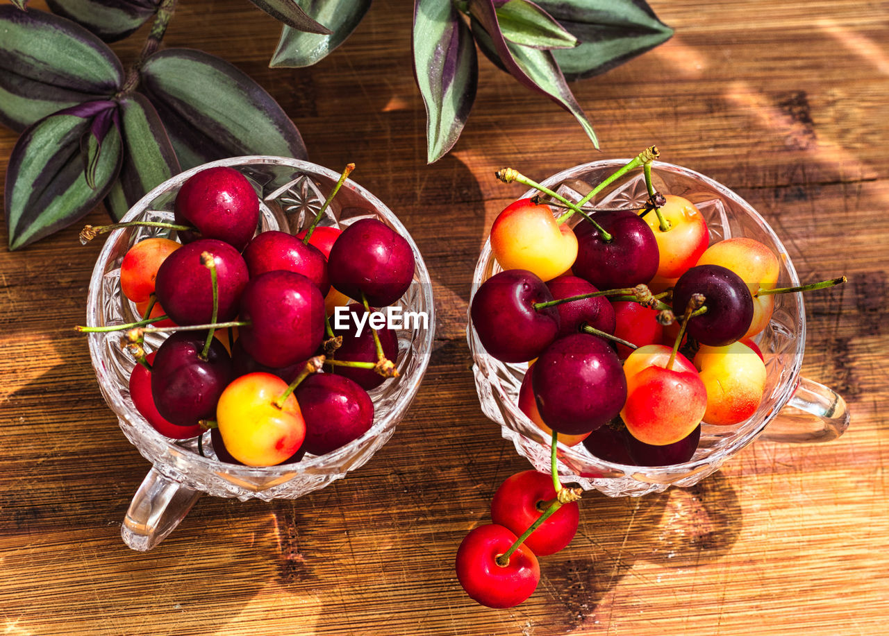 Two crystal cherry cups on a wooden table, top view. high angle view of fruits on table.