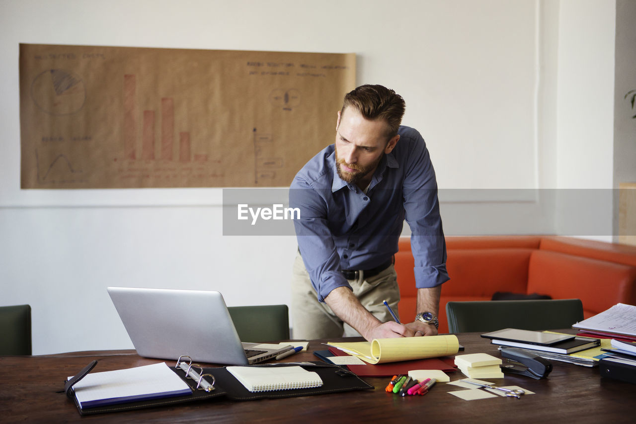 Man writing on document while working in office