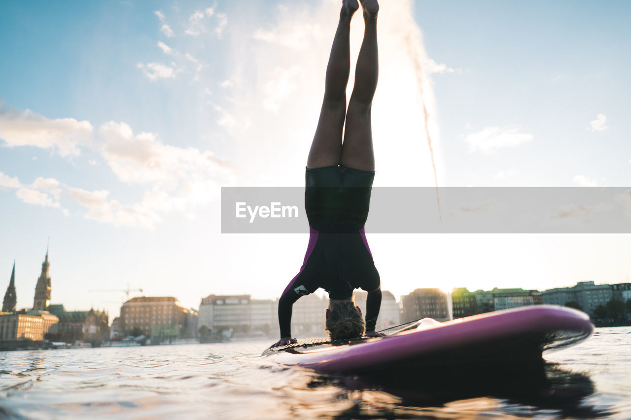 FULL LENGTH OF WOMAN WITH ARMS OUTSTRETCHED AGAINST SKY