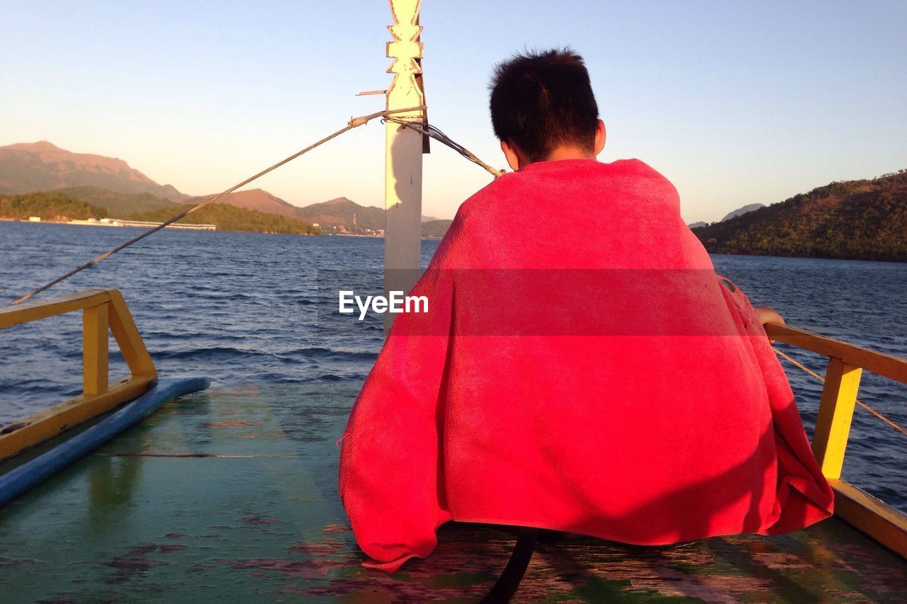 WOMAN SITTING ON PIER IN LAKE