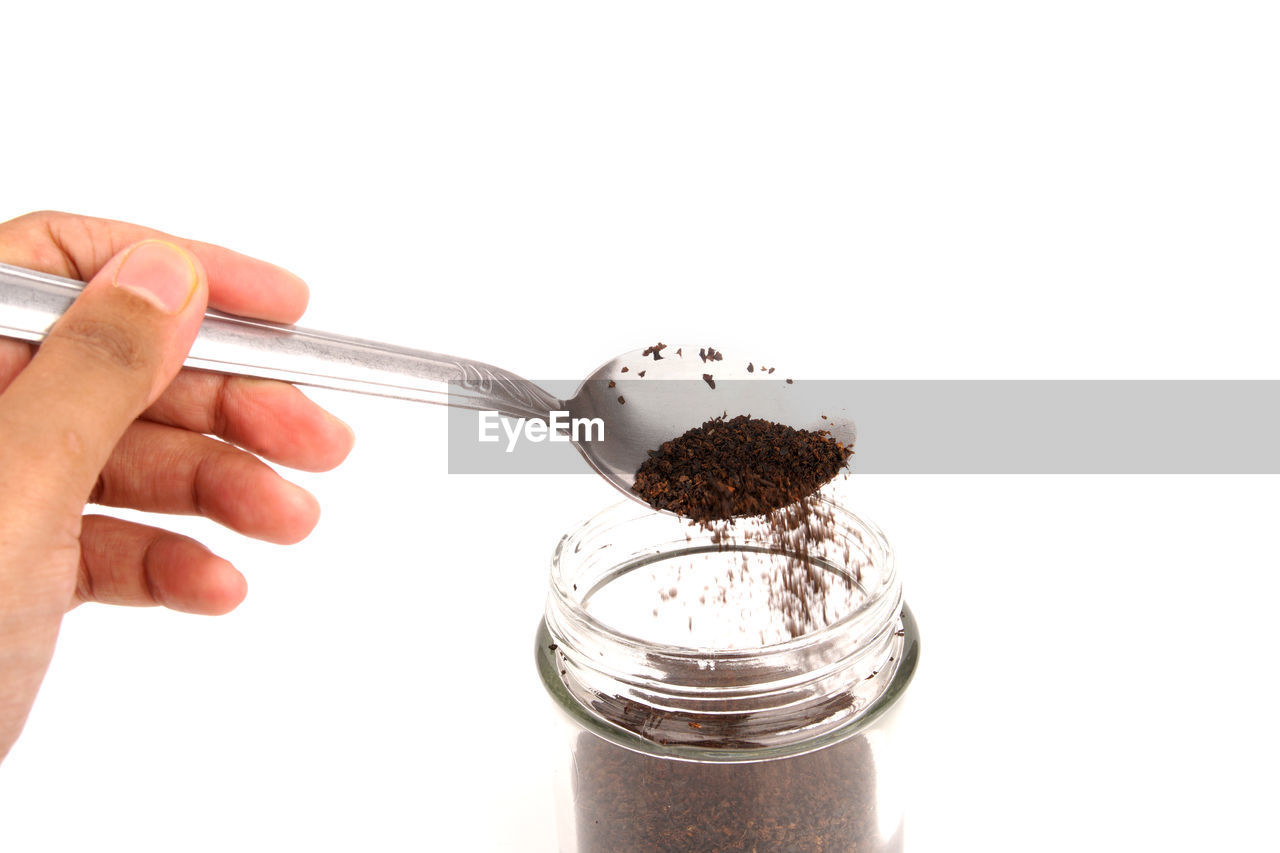 CLOSE-UP OF HAND HOLDING TEA AGAINST WHITE BACKGROUND