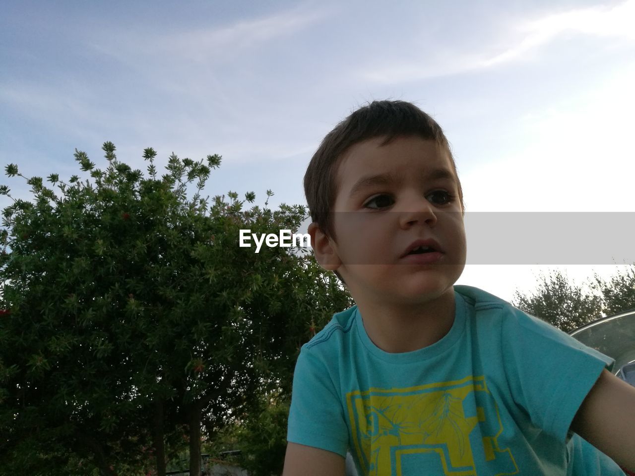 Low angle view of boy looking down against sky