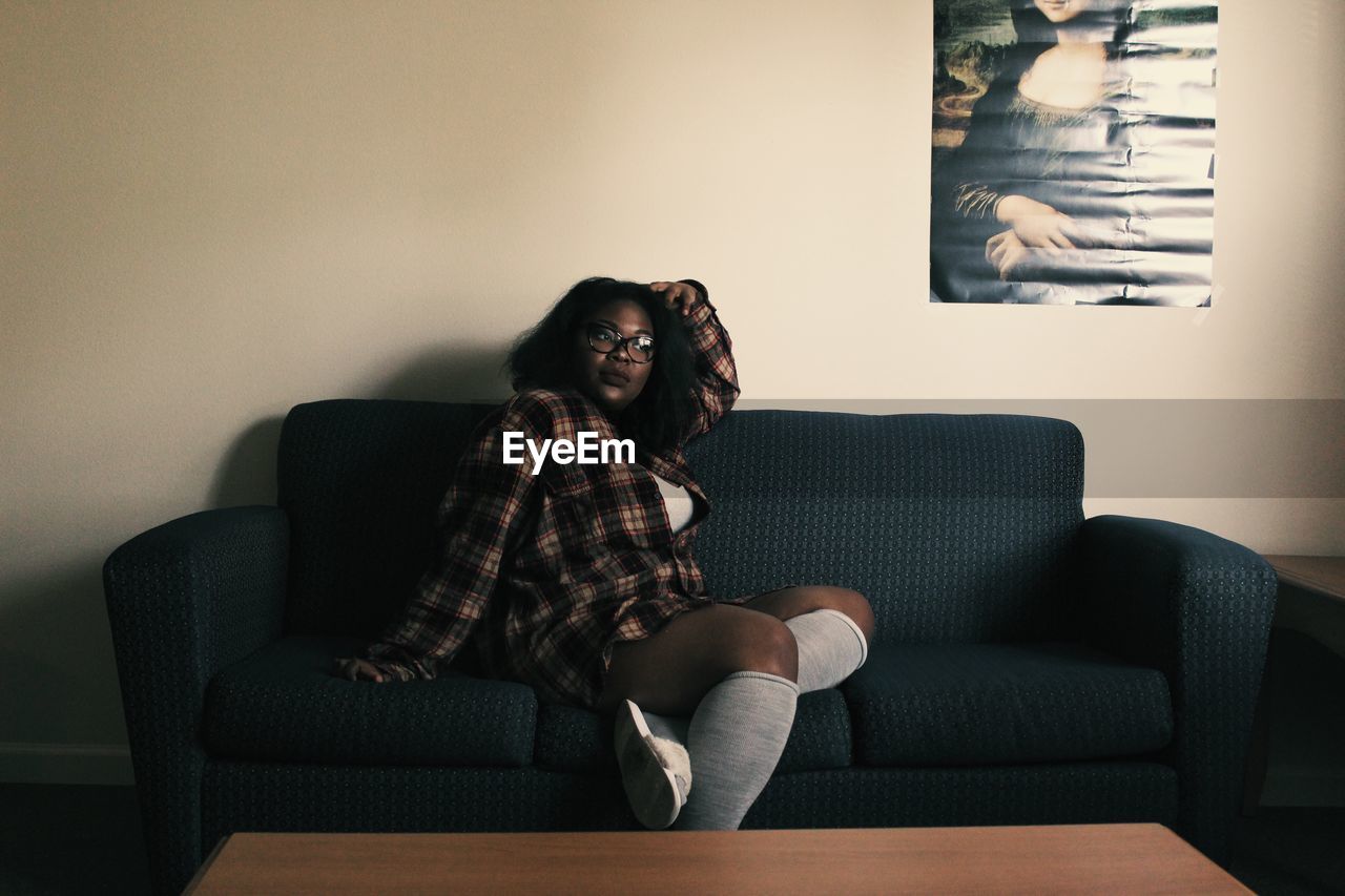 YOUNG WOMAN SITTING ON COUCH