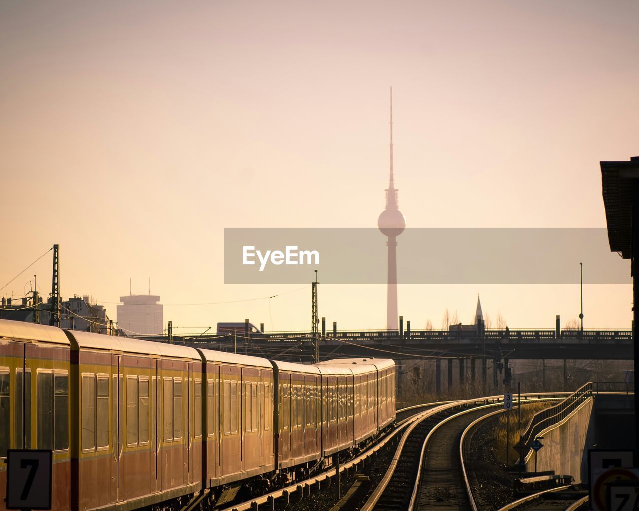 Train by fernsehturm against clear sky at sunset