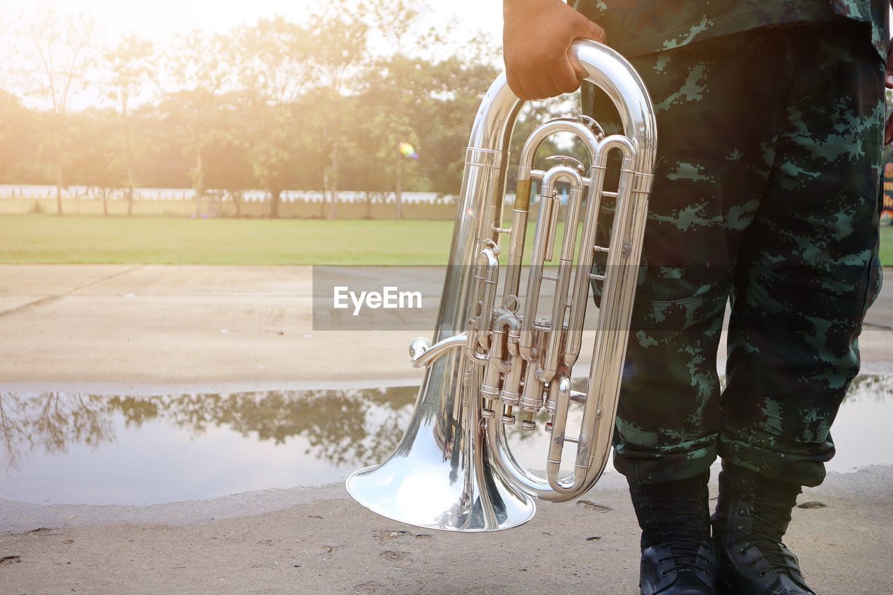 Midsection of army soldier holding saxophone