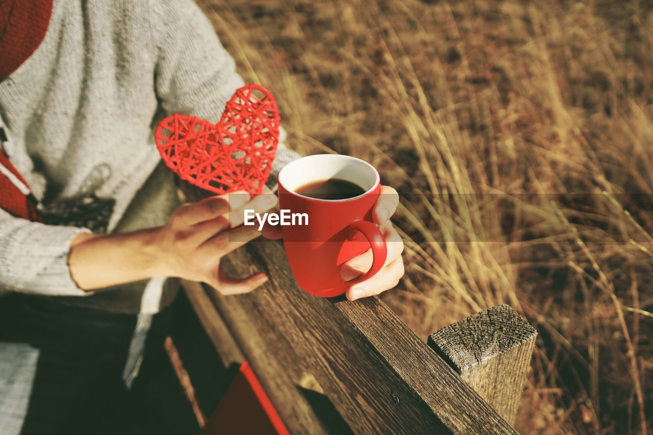 MIDSECTION OF WOMAN HOLDING COFFEE