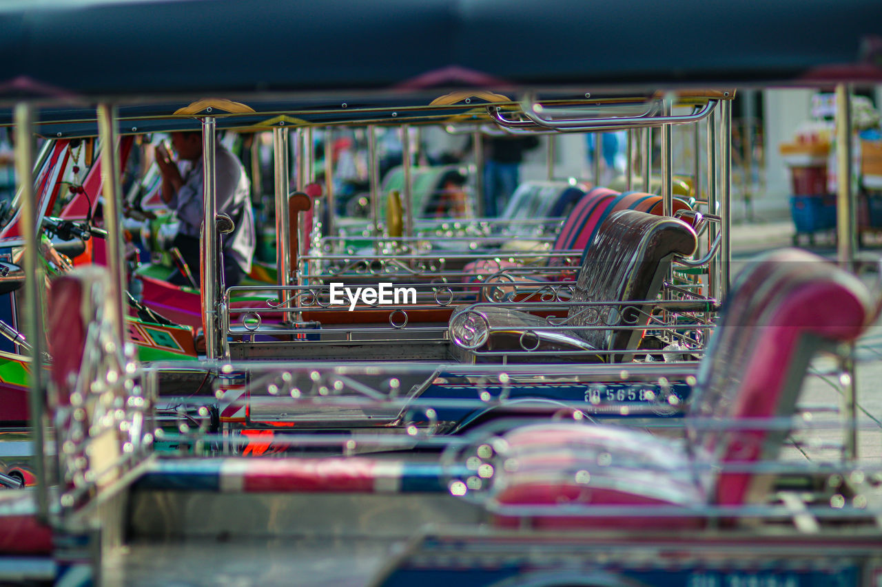 amusement park, amusement ride, no people, vehicle, selective focus, large group of objects, in a row, abundance, indoors, retail, multi colored, metal