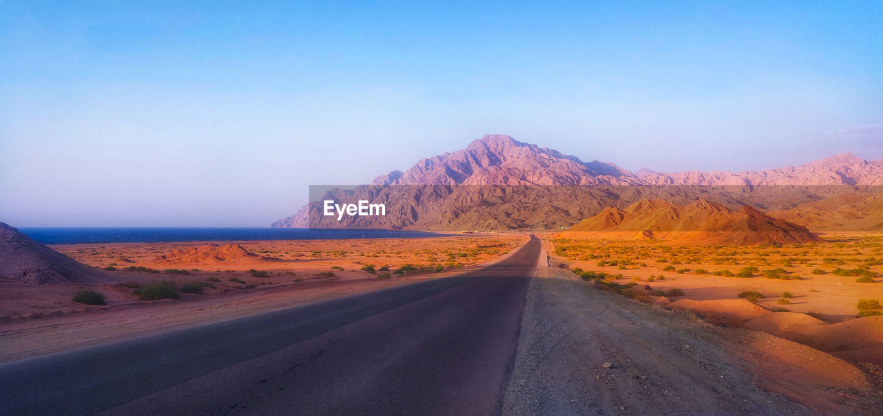 Country road amidst desert against sky