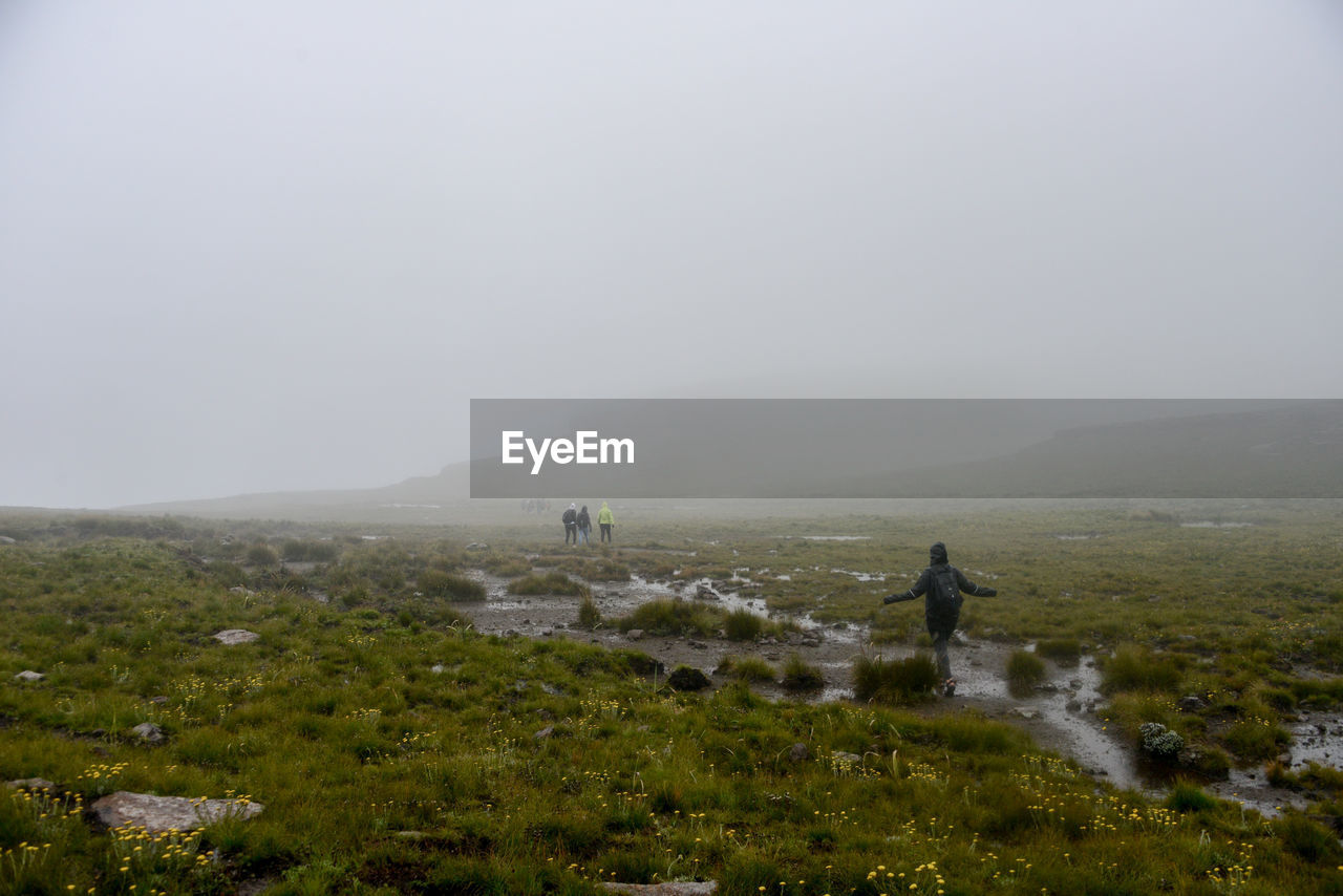 Hikers walking on landscape during foggy weather